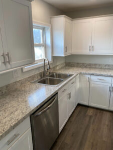 A Modern L-Shaped Kitchen with White Cabinets, Granite Countertops