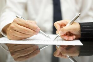 Closeup of male hand pointing where to sign a contract, legal papers or application form.